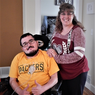 A man with yellow shirt sitting in a wheelchair next to a woman with a red shirt 
