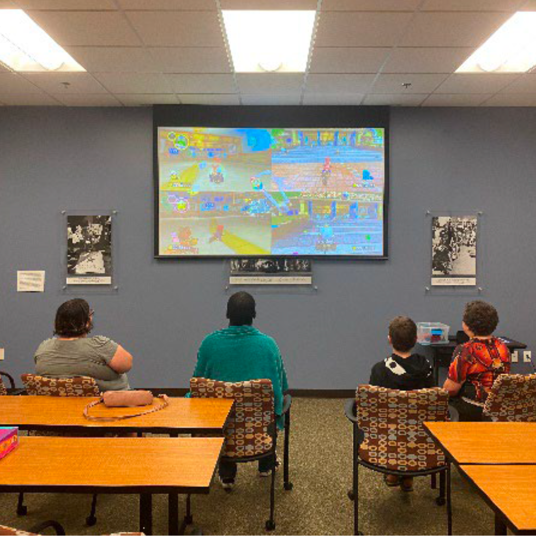 A group of youth and adults play a video game together