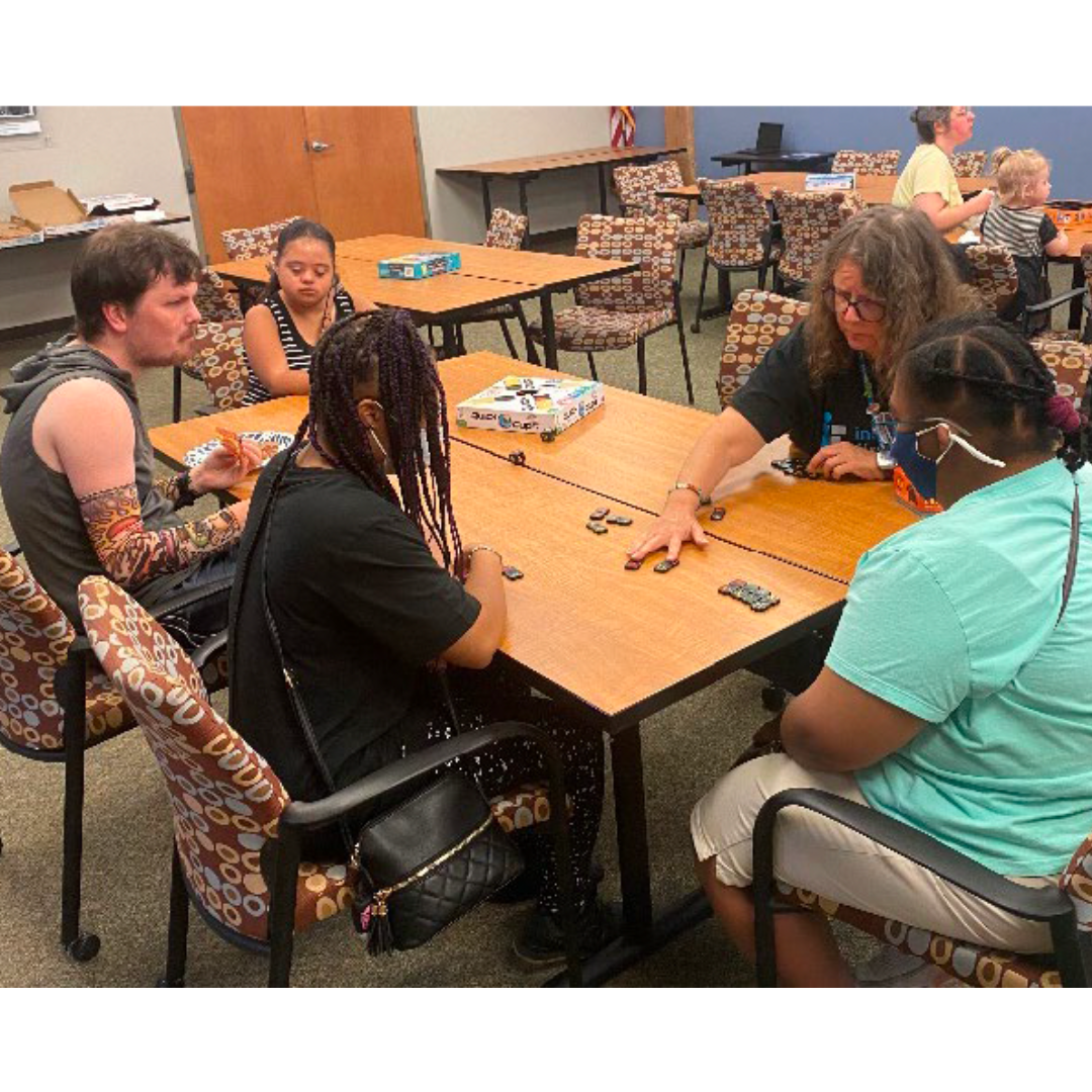 A group of people gathered around a table play a board game