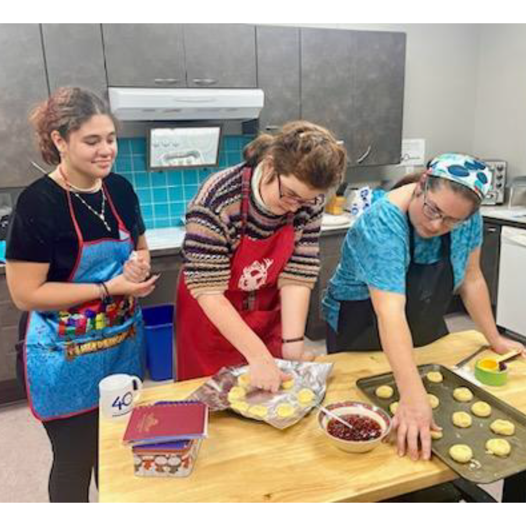 Photo of three people baking holiday cookies in a kitchen