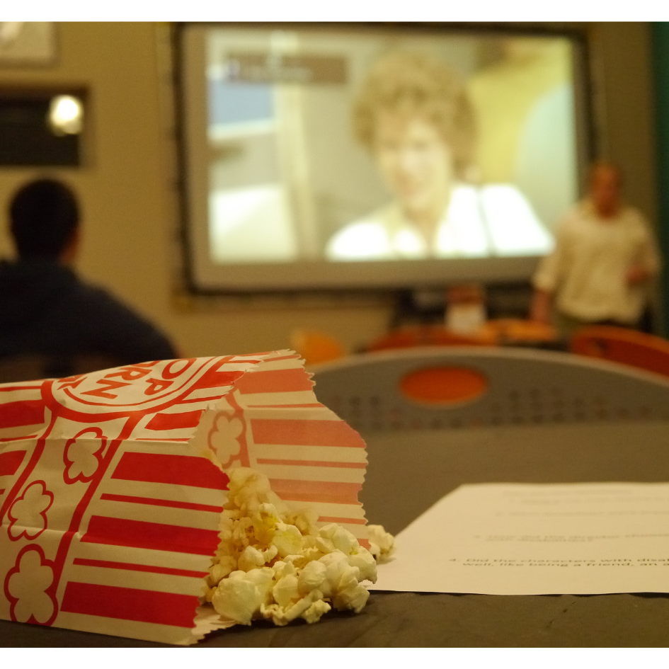 A bag of popcorn with a movie in the background