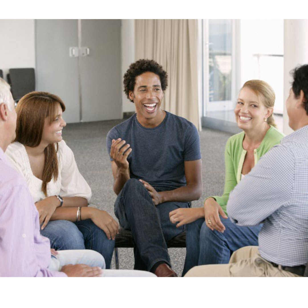 Photo of people of different ages sitting in a circle talking and smiling